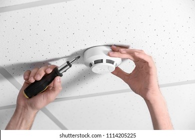 Young Male Technician Installing Smoke Alarm System Indoors