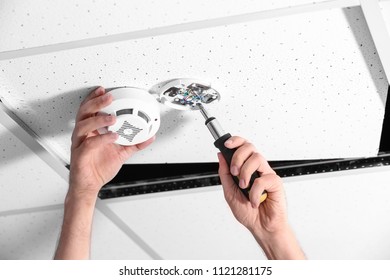 Young Male Technician Installing Smoke Alarm System Indoors