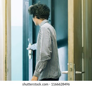 Young Male Teenager In Checkered Shirt Leaving Home And Closes The Door 