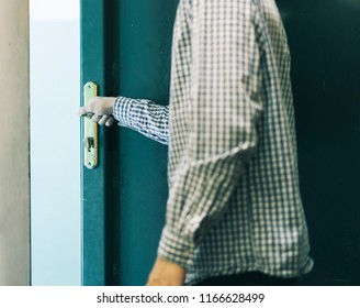 young male teenager in checkered shirt leaving home and closes the door 