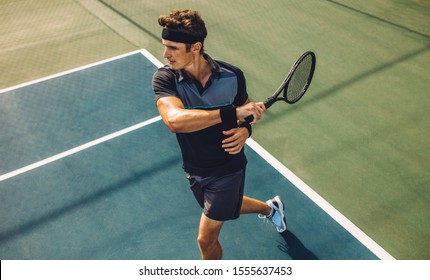 Young Male Tennis Player Hitting Forehand During Practice Game On Hard Court. Pro Tennis Player Playing Tennis On Court.