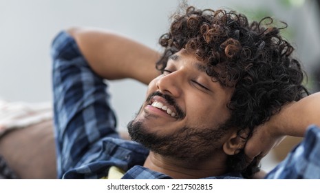 Young Male Throwing His Hands Behind His Head Thinks Of Something Good And Smiles. Portrait Of Happy Asian Man Lying On Sofa Resting. Relax At Home, Positive Thinking