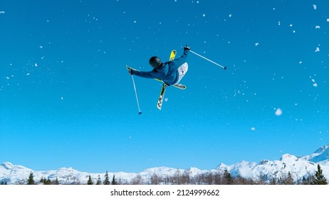 Young male tourist on skiing trip rides around the fun park and does breathtaking tricks. Freestyle skier takes off the kicker and does a difficult high flying 360 grab. Athletic traveler skiing.