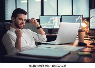 Young Male Trader At Office Work Concept Sitting Looking At Laptop Happy