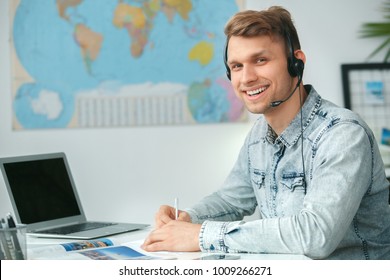 Young Male Travel Agent Consultant In Tour Agency Wearing Headset