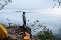 A Young Male Traveler Stands On A Rock At A Cliff Filled With Morning Mist In His Camp.
