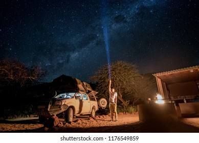 Young male traveler using flashlight crossing the southern milky way at campsite in Namibia, Africa. Road trip travel with stargazing concepts - Powered by Shutterstock