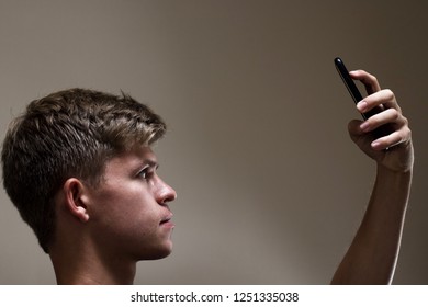 A Young Male Uses Facial Recognition Technology To Unlock A Modern Smartphone. Vague Sense Of Unease.