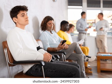 Young male visitor waiting for his turn sitting on chair in hall of health center - Powered by Shutterstock