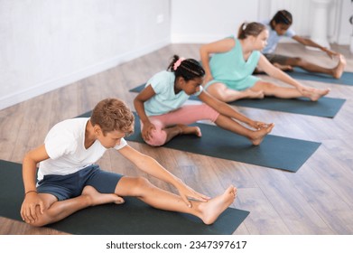 Young male visitor of yoga class engaged Pilates in sports studio hall. oy child stretches and prepares to perform Jana Shirshasana - Powered by Shutterstock