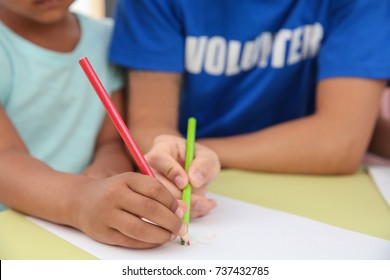 Young Male Volunteer Drawing With Little Child, Closeup. Volunteering Abroad Concept