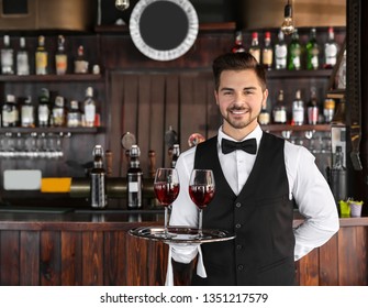 Young Male Waiter With Glasses Of Wine In Restaurant