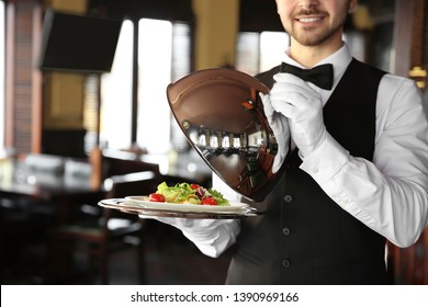Young Male Waiter With Salad In Restaurant