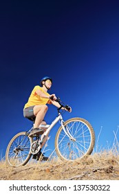 A young male wearing yellow shirt and helmet on a mountain bike