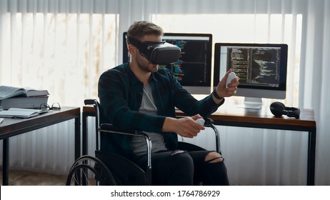 Young male web developer in a wheelchair wearing virtual reality headset, working in the modern office. Multiple computer screens with program code. Focus on a man. Disability concept. IT software - Powered by Shutterstock