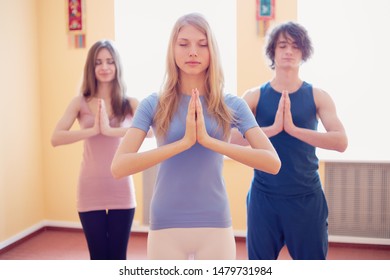 Young Male Yoga Teacher Teaching Yoga To A Group Of Students In A Yoga Studio.