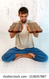 A Young Male Yogi Sits In The Lotus Position. In Each Hand, A Man Holds A Wooden Sadhu Board With Nails.