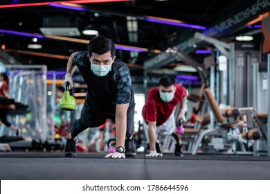 young mam and friend working out wearing surgical mask & latex rubber gloves, COVID-19 pandemic social distancing rules while working out in  a gym, new normal & social distancing concept