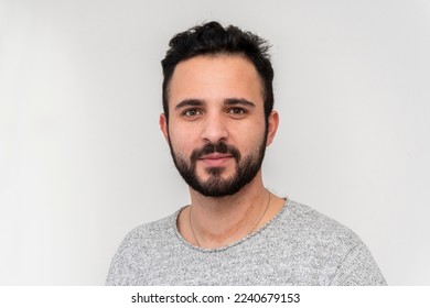 a young man 25-30 years old with a beard on a white background looks directly into the camera.