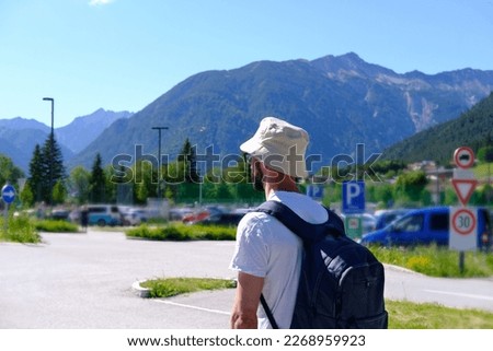 young man 30 years old, backpacker in panama, tourist with blue backpack on back walks along road with magnificent natural scenery, high alpine mountains, watching nature, travel, summer vacation