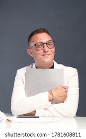 A Young Man Of 30-35 Years Old In A White Jacket, Black Turtleneck, Glasses And A Short Haircut Holds An Empty Sign In His Hands. Template For Design, Mockup.