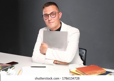 A Young Man Of 30-35 Years Old In A White Jacket, Black Turtleneck, Glasses And A Short Haircut Holds An Empty Sign In His Hands. Template For Design, Mockup.