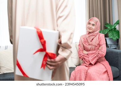 The young man is about to give a gift to the young woman. - Shutterstock ID 2394545095