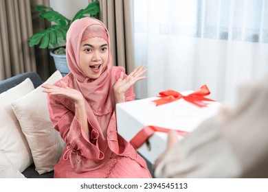 The young man is about to give a gift to the young woman. - Shutterstock ID 2394545113