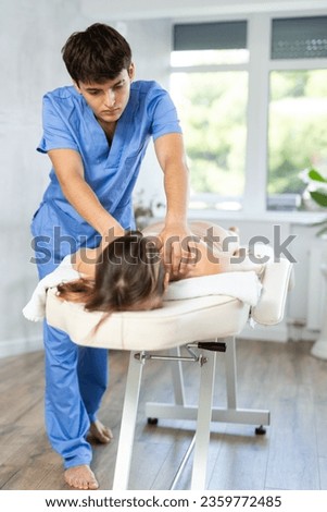 Young man actively rubs lower back of young woman during general massage procedure. Gentle massage of problem areas, prevention of back pain, relief of fatigue