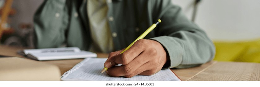 Young man of African American descent engaged in writing in a notebook with a pen. - Powered by Shutterstock