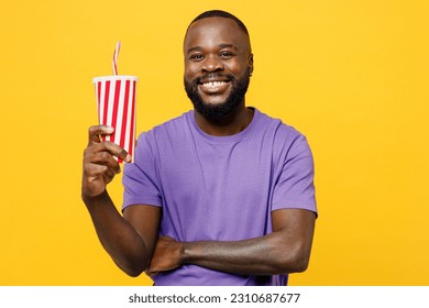 Young man of African American ethnicity wear casual clothes purple t-shirt look camera hold in hand cup of soda cola fizzy water isolated on plain yellow background studio portrait. Lifestyle concept - Powered by Shutterstock