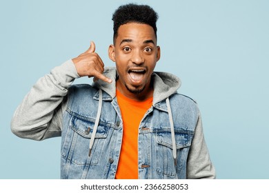 Young man of African American ethnicity wear denim jacket orange t-shirt doing phone gesture like says call me back isolated on plain pastel light blue background studio portrait. Lifestyle concept - Powered by Shutterstock