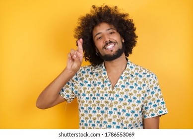 Young man with afro hair over  wearing hawaiian shirt standing over yellow background pointing up with fingers number ten in Chinese sign language Shi
