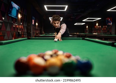 Young man aiming with billiards cue