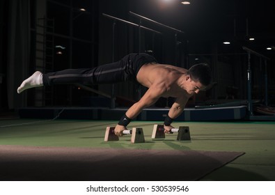 Young Man, In Air, Gymnast, Two Hands Cartwheel. Indoors, Dark Hall.