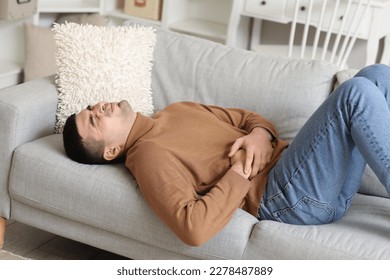 Young man with appendicitis lying on sofa at home - Shutterstock ID 2278487889
