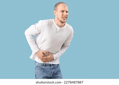 Young man with appendicitis on blue background - Shutterstock ID 2278487887