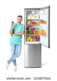 Young Man With Apple Near Open Refrigerator On White Background