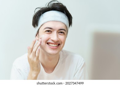 Young Man Applying Cream To His Face