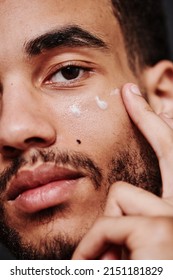 Young Man Applying Cream On His Face