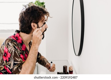 Young Man Applying Eyelashes Sitting At A Dressing Table. Transgender Guy Putting On Makeup At Home. LGTBI And Diversity People Concept. High Quality 4k Footage