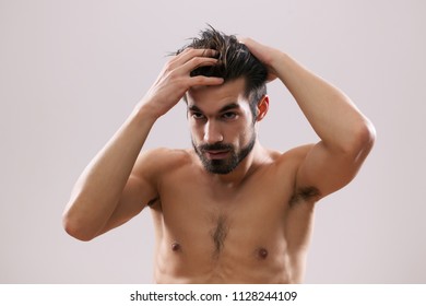 Young Man Is Applying Hair Gel To His Hair. 