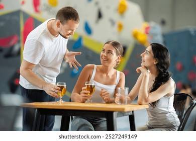 Young man approached to meet two young women sitting at table on climbing wall - Powered by Shutterstock