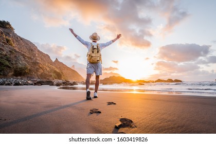 Young man arms outstretched by the sea at sunrise enjoying freedom and life, people travel wellbeing concept	
