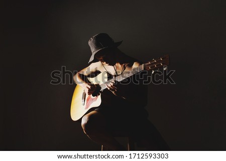 Young man, Asian, playing acoustic guitar, composing music, in his room, to relax, feeling
