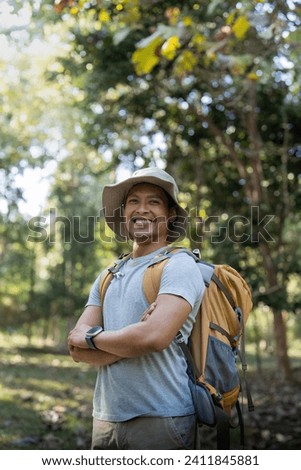 Young man asian trekking among trees with backpack, young man enjoy alone in forest. Camping, hiking, travelling, search for adventure concept
