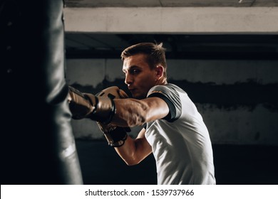 Young Man Athlete Boxing Workout In Fitness Gym On Dark Background.Athletic Man Training Hard.Kick Boxing Concept