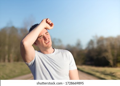young man athlete received sun and heat stroke and headache. guy holds his head with his hands and protects himself from the sun in outdoors. copy space, place for text