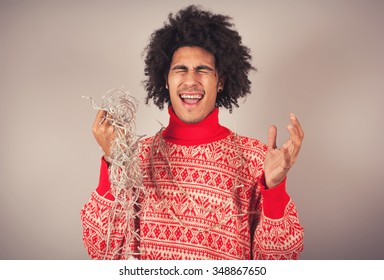 Young Man Attempts To Untangle A String Of Christmas Lights