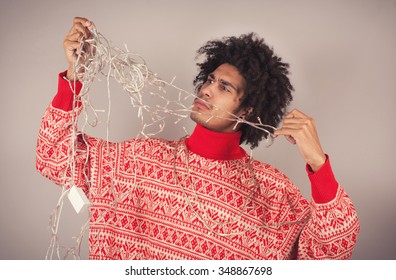 Young Man Attempts To Untangle A String Of Christmas Lights